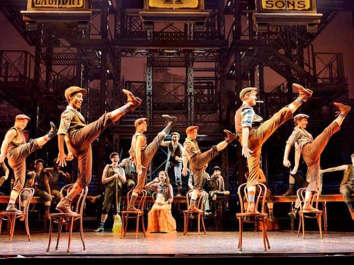 Newsies musical cast high kicking off of individual chairs