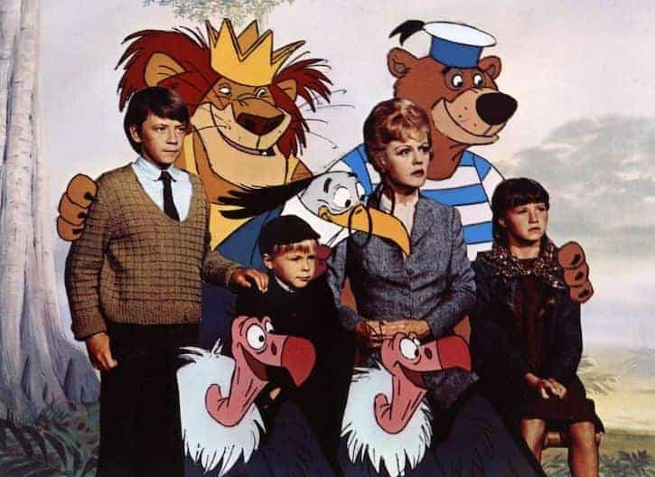 Bedknobs and broomsticks cast posing with a bear, lion, bird, and two vultures