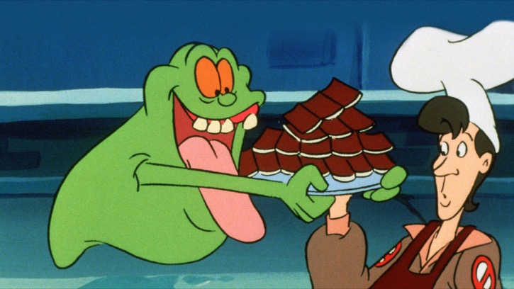 Slimer from the Ghostbusters cartoons eating a tray of small cakes